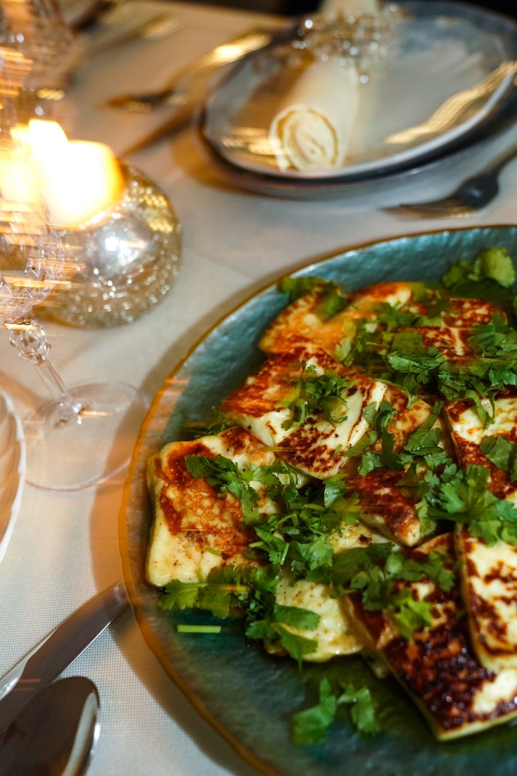 Grilled halloumi with fresh herbs beside candlelight